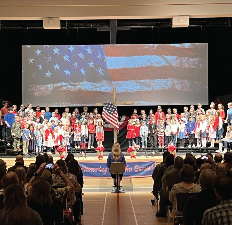 Calvary school stage with the American flag and cross