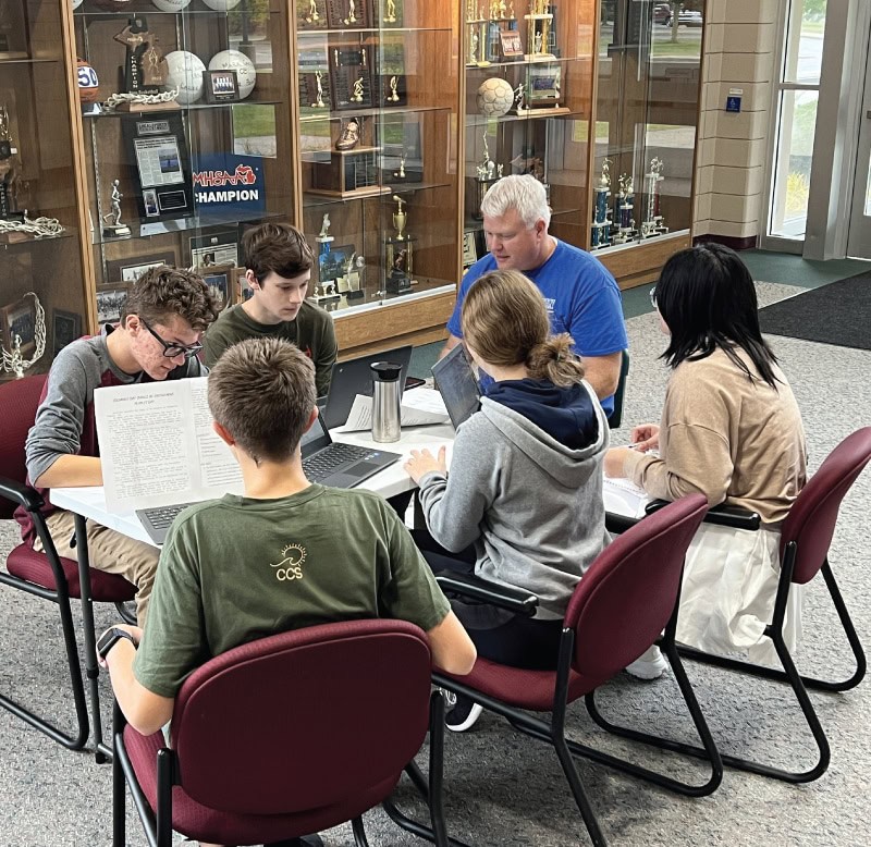 students with computers around table doing homework